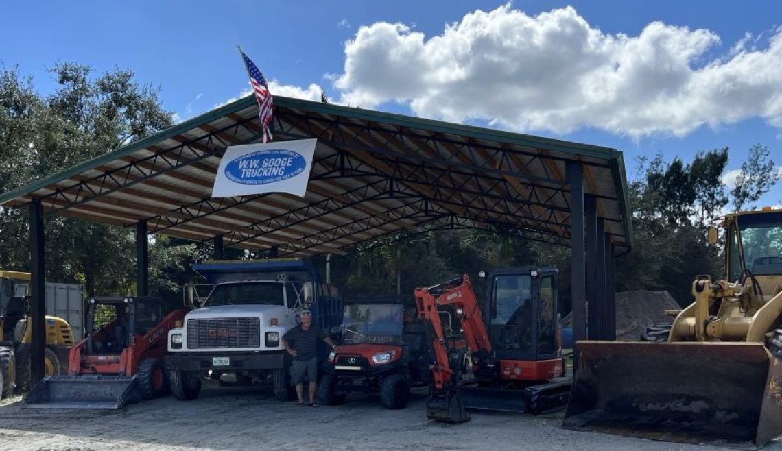 Industrial vehicles and equipment parked under a large metal roof.