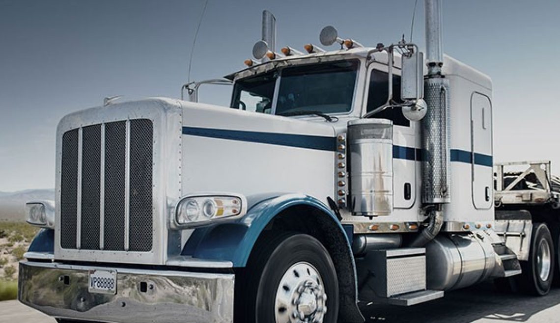 Close-up of a blue and white semi-truck cab on a clear day.